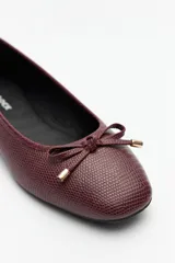 Balerinas negras de símil cuero texturizado con aplique de moña y detalles metálicos.