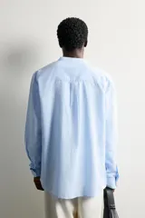 Camisa de corte relajado, confeccionada en mezcla de lino y algodón. Presenta cuello tipo mao, manga larga con puño abotonado y cierre frontal con botones.