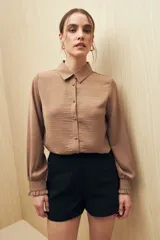 Camisa color café con textura sutil, cuello clásico, botones forrados a tono y mangas largas con puños fruncidos.