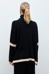 Polera de tejido de punto con cuello alto, diseño holgado y detalles en color contraste en los laterales y ruedo.