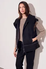 Chaleco negro con cuello de piel sintética, cierre frontal con cremallera y corte oversize.
