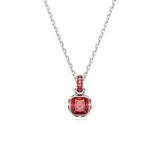 Colgante con cadena de eslabones plateados y un dije principal con una piedra roja de talla cuadrada rodeada de cristales rojos más pequeños. El engarce del dije es plateado.