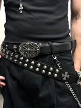 Cinto de cuero negro con tachas cónicas metálicas y hebilla plateada con diseño grabado de rosas y cruz.