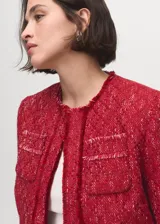 Chaqueta de tweed color rojo, de diseño recto, cuello redondo y manga larga. Cuenta con terminaciones deshilachadas y cuatro bolsillos de parche delanteros.