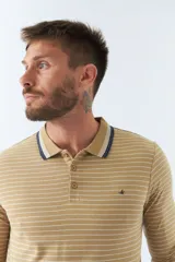 Chomba manga larga color beige con rayas horizontales blancas, cuello polo con borde azul marino y logo bordado en el pecho.