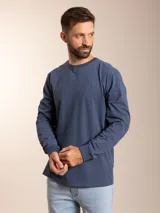 Remera azul de manga larga con cuello redondo y logo bordado en el pecho.