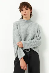 Polera gris de tejido tramado, cuello alto y mangas holgadas.