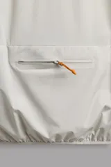 Chaleco técnico de corte regular con cuello subido y cierre frontal de cremallera. Presenta un diseño ligero con panel frontal ligeramente acolchado, bolsillos laterales con cremallera oculta y un bolsillo adicional en el pecho con tirador en color naranja. Incluye acabados con cinta elástica en el bajo y detalle de logo estampado.