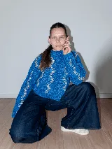 Sweater tejido a mano con lana merino color negro y bordado con lana color crudo. Es corto, a la cintura y de cuello alto.