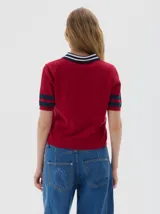 Remera tejida tipo polo, color rojo, con cuello azul marino y rayas blancas. Tiene botones frontales, largo cropped y mangas cortas con franjas azules.