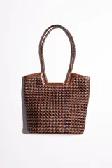 Bolso tipo tote bag de cuero trenzado a mano, en tonos marrón y negro, con asas trenzadas.