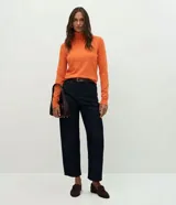 Suéter de punto color crema con cuello alto y mangas largas. Presenta un diseño ajustado al cuerpo con puños acanalados.