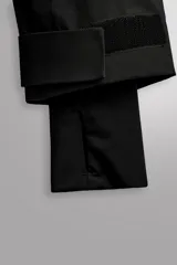 Cazadora deportiva de esquí en color negro, confeccionada en tejido técnico impermeable de tres capas con costuras y cremalleras termoselladas. Cuenta con capucha ajustable, ventilación en axilas, puños con ajuste de tira adherente y puño interior elástico con abertura para el pulgar. Incluye sistema de rescate RECCO y faldón interior para protección contra el frío.