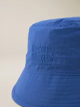 Gorro tipo bucket color celeste con logo bordado "Benson & Thomas Modern Classics" en el frente.