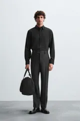 Camisa negra de corte slim fit, con cuello italiano y manga larga con puño abotonado. Cierre frontal de botonadura.