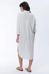 Vestido camisero blanco de lino, corte oversize, con cuello camisero, mangas largas y cierre frontal con botones.