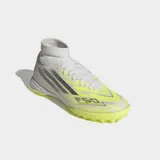 Championes de fútbol Adidas F50 Sparkfusion League para pasto sintético. Presentan un diseño de caña media con cuello de tejido de punto, exterior Fiberskin con texturas 3D y suela de caucho con tapones para tracción en superficies artificiales. Combinan tonos blanco, gris y amarillo neón.
