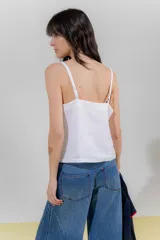Top negro con rayas verticales blancas, escote en V y breteles finos regulables con detalle de borlas.