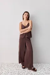 Pantalón wide leg de tiro medio y calce amplio, color marrón, con pinzas delanteras, cierre frontal y bolsillos laterales funcionales.