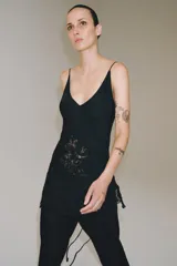 Top satinado de viscosa color negro, con escote en V, tirantes finos y detalles de bordados a tono en la parte inferior.