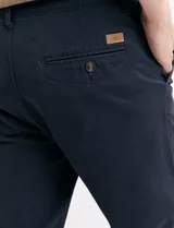 Pantalón de vestir marrón, de corte recto, con bolsillos laterales y traseros. Se ajusta a la cintura con cinturón de cuero marrón.