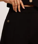 Short sastre de cintura alta color marrón, con bolsillos laterales y detalles de tachuelas metalizadas.