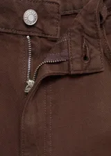 Jeans wide leg tiro alto color marrón, confeccionados en 100% algodón, con diseño de cinco bolsillos, trabillas y cierre frontal con cremallera y botón.