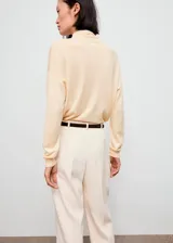 Jersey de punto fino color beige, con cuello alto y mangas largas de diseño recto.