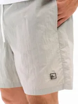 Short de baño negro de taslon de secado rápido, con moldería clásica, cintura elástica con cordón blanco para ajuste y un pequeño parche cuadrado con una letra 'F' en la parte inferior izquierda.