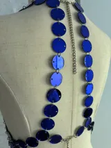 Top tipo corpiño confeccionado con círculos metálicos unidos por pequeñas cadenas, color azul eléctrico. Se ajusta con cadenitas en la espalda y el cuello.