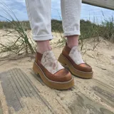 Zapatos de cuero estilo botineta baja en combinación de tonos marrones y beige, con suela chunky de plataforma plana y diseño texturizado en el talón.