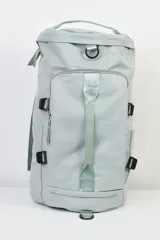 Bolso mochila color gris claro con múltiples bolsillos y correas ajustables.