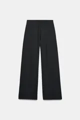 Pantalón de tiro alto con pierna ancha, confeccionado en sarga color tostado. Presenta detalle de doble hilera de botones metálicos dorados en el frente y pinzas verticales.