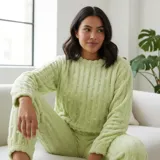 Pijama de dos piezas de tejido plush texturado con diseño de puntos en relieve, compuesto por un buzo de manga larga con cuello redondo y un pantalón largo de corte recto.