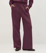 Pantalón wide leg de felpa color bordó, con cintura elástica, bolsillos laterales y costuras frontales decorativas.