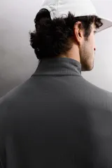 Camiseta de manga larga negra, confeccionada en tejido técnico ligero y elástico. Tiene cuello alto con cremallera, corte slim fit, bolsillo frontal con cremallera y puños con cinta a contraste.