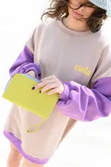 Billetera grande de cuero color verde pistacho, con cierre de cremallera y correa de mano.