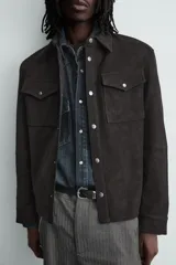 Sobrecamisa de corte relajado confeccionada en tejido efecto piel color marrón oscuro. Presenta cuello solapa, cierre frontal con botones metálicos, mangas largas con puños abotonados y dos bolsillos de plastrón con solapa en el pecho.