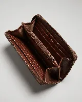 Billetera rectangular de cuero marrón con cierre perimetral y correa de muñeca. Presenta un diseño decorativo con costuras en forma de X en la parte frontal.