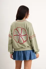 Campera oversize color crudo de algodón con spandex, corte de largo intermedio, mangas largas con detalles de costuras en zigzag bordadas y un gran diseño bordado a mano de una flor en la espalda.