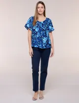 Blusa de poliéster azul con estampado botánico y floral, de silueta holgada y fluido diseño. Cuenta con escote redondo elastizado con frunces y mangas cortas amplias.