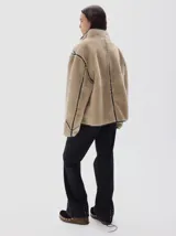 Campera de pelo sintético en color azul, con cuello alto y cierre frontal de botones. Presenta detalles de terminación en cuero vegano color bordó en los bordes, costuras y solapas.