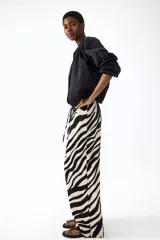 Pantalón largo de corte holgado y piernas amplias con estampado animal print de cebra. Cuenta con tiro alto, cintura elástica y cordón ajustable.