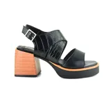 Sandalia de cuero sintético color negro, con tira ancha sobre el empeine y tira con textura de cocodrilo alrededor del tobillo. Tiene plataforma y taco cuadrado de madera.