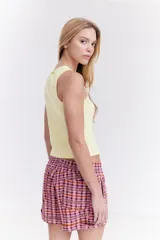 Top musculosa blanco de canalé con cuello redondo, corte ajustado y detalle de botones a presión en el lateral.