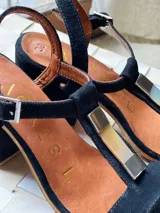 Sandalias de gamuza azul marino, de taco bajo, con tira en forma de T adornada con una placa central de nácar y alpaca, y tira ajustable al tobillo.
