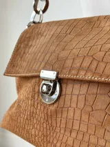 Cartera bandolera de cuero marrón con textura croco, solapa frontal, cierre metálico de giro plateado y correa de cadena con eslabones.