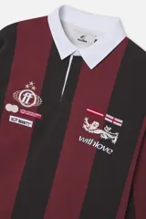 Polo de manga larga con rayas verticales en borgoña y negro, cuello de contraste blanco y cierre frontal parcial con botones ocultos. Presenta diversos bordados y parches decorativos en el pecho.