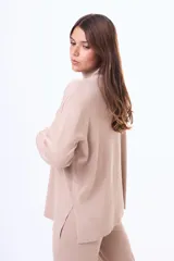 Buzo tejido de punto color negro, con cuello alto, manga larga y corte holgado con aberturas laterales en el ruedo.