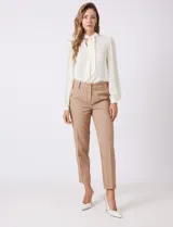 Pantalon de corte cigarette en color beige, confeccionado en tejido con apariencia denim y acabado satinado. Presenta tiro medio-alto, largo tobillero, cintura con presillas, cierre con gancho sastrero oculto, bolsillos laterales diagonales con botones forrados y pinzas traseras para un ajuste entallado.